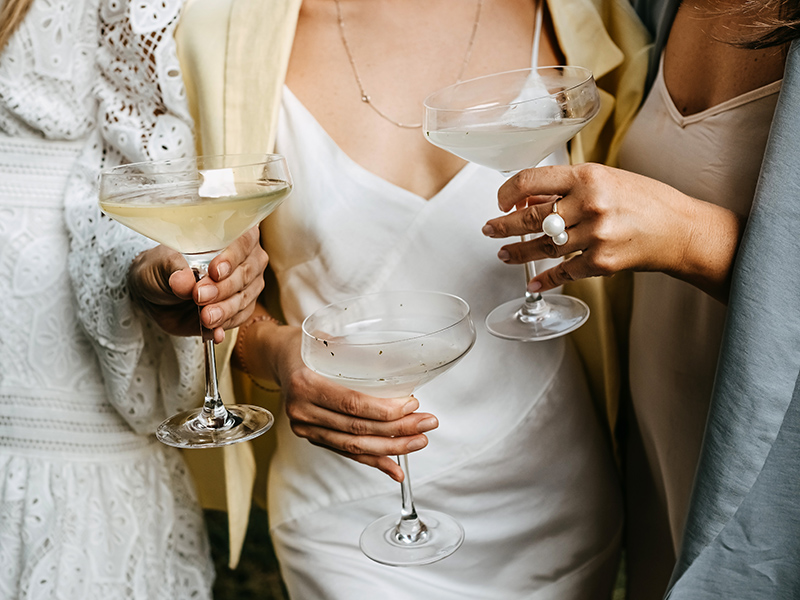 Women wearing summer dresses, holding coupes with champagne at a