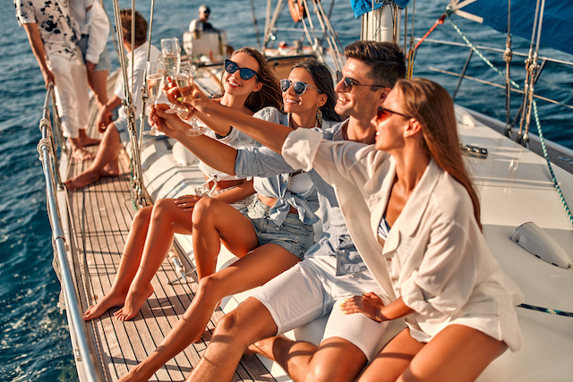 Group of friends relaxing on luxury yacht and drinking champagne. Having fun together while sailing in the sea. Traveling and yachting concept.