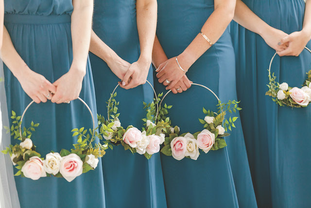 Bridesmaids,Hips,Down,In,Teal,Dresses,Holding,Flower,Wreath,Hoops Bridesmaids hips down in teal dresses holding flower wreath hoops with pink flowers.